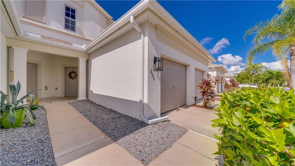 Entrance and garage of condominium unit 203 at 14721 Calusa Palms Dr with tropical plants and palm trees