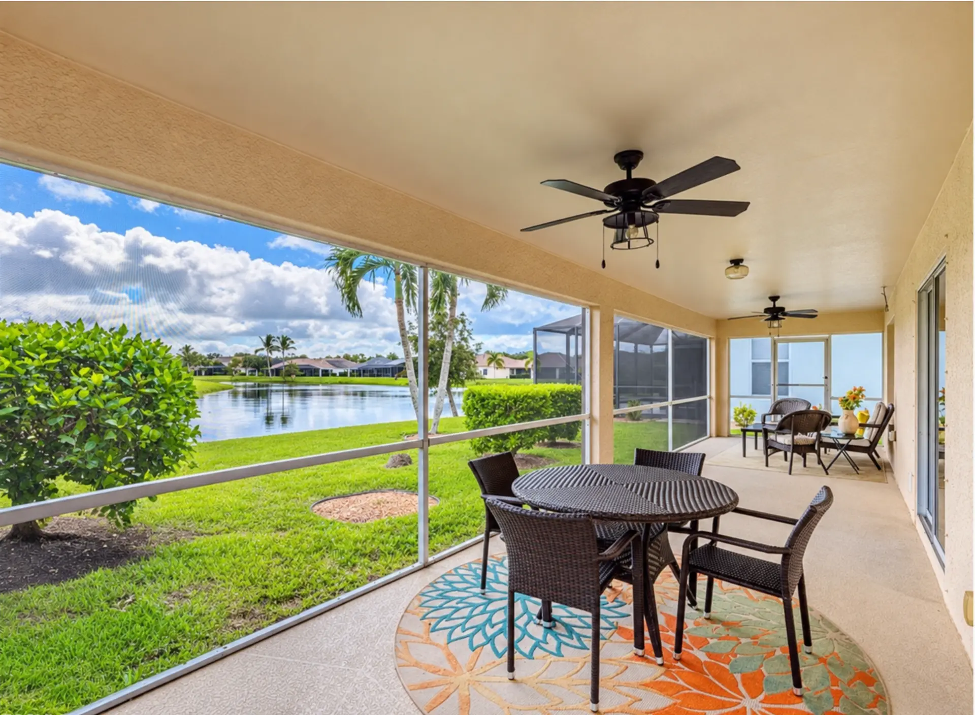 Screened lanai of 14565 Calusa Palms Dr with patio furniture overlooking the lake and palm trees