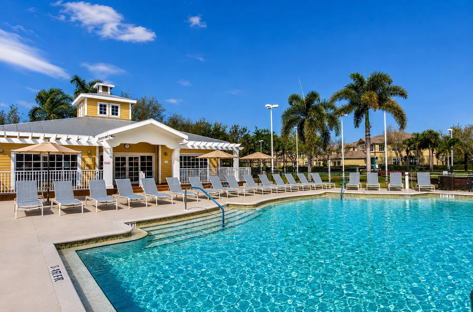 The Calusa Palms clubhouse pool with lounge chairs and palm trees on a sunny day