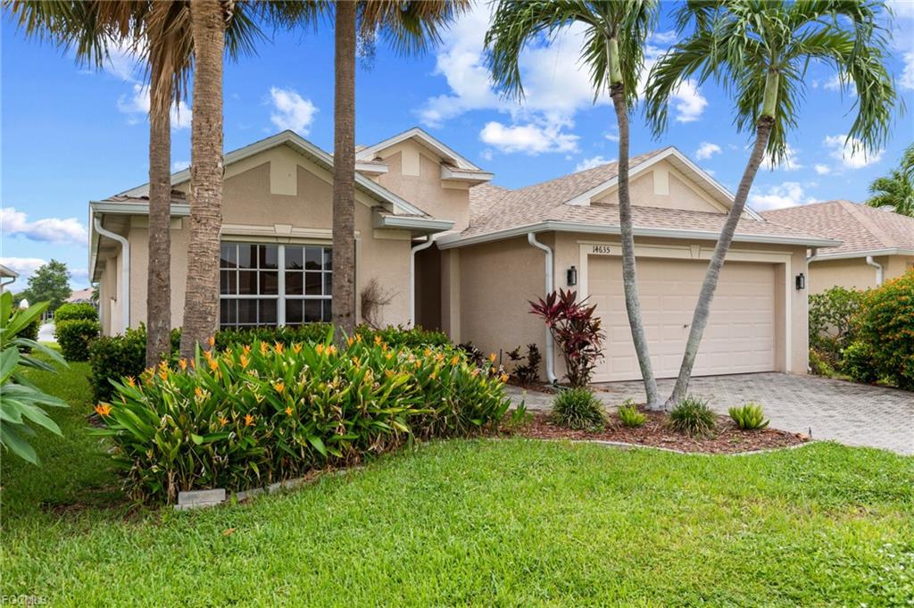 Single family home at 14635 Calusa Palms Dr with a two-car garage, tall palm trees and flowering bird of paradise plants